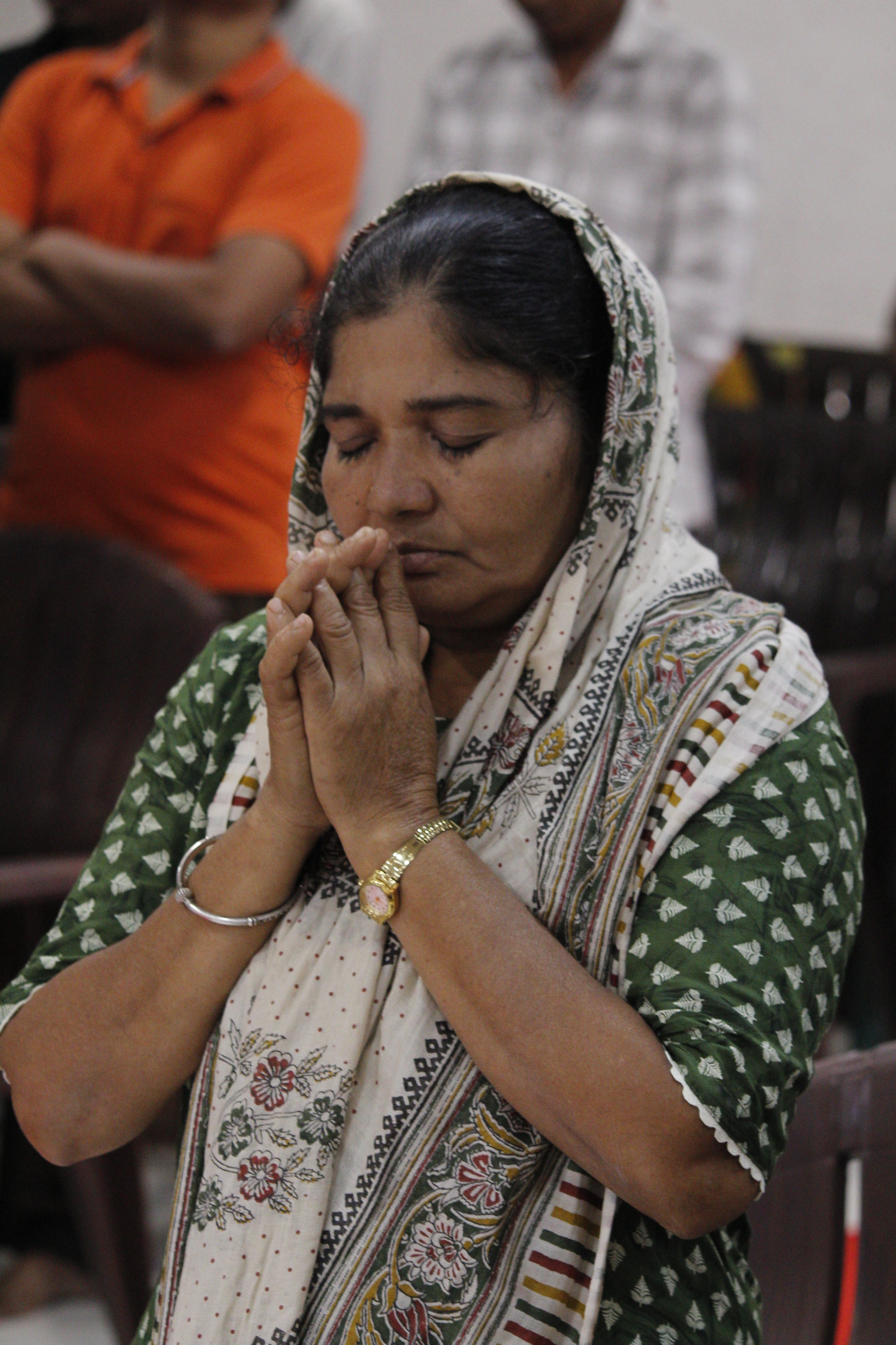 Devotee praying with clasped hands at a BFN service